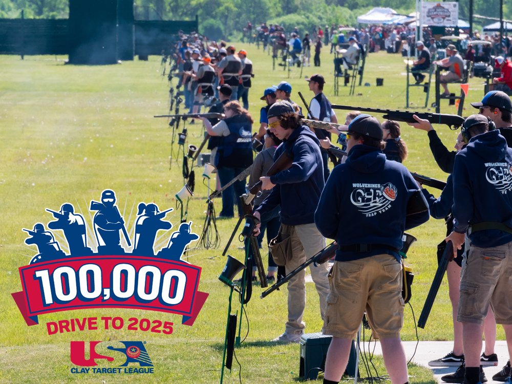 A group of people standing in a field with a banner that says 100,000 drive to 2025.